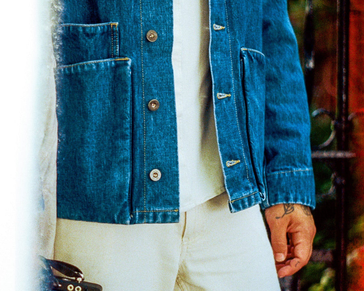 Person wearing a blue denim jacket and white pants with a blurred background