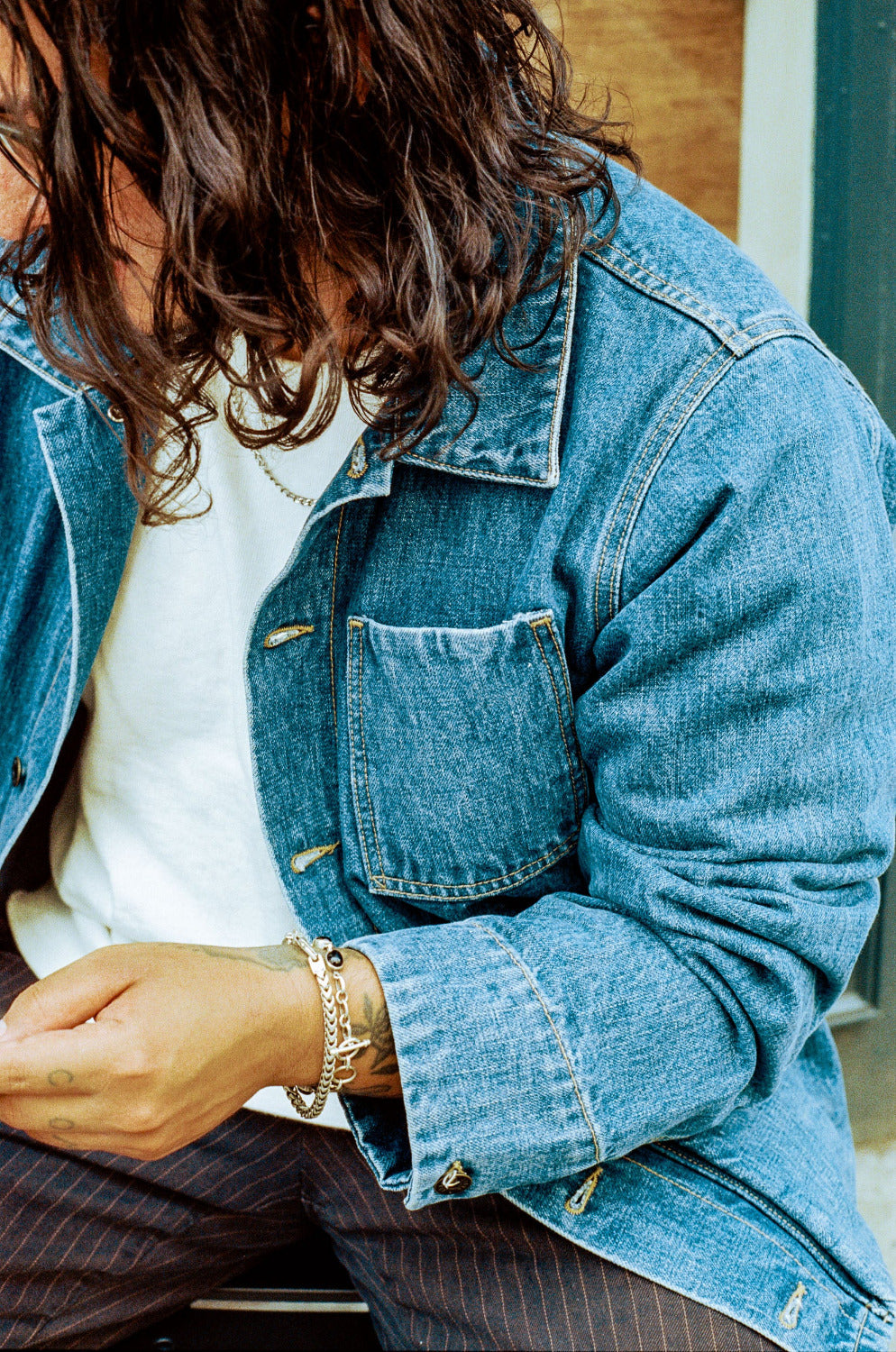 Person wearing a blue denim jacket with a white shirt underneath.