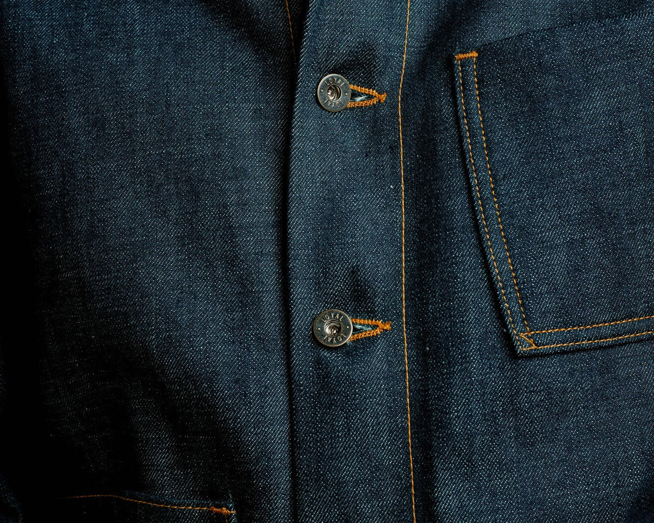 Close-up of a blue denim jacket with buttons and stitching details.