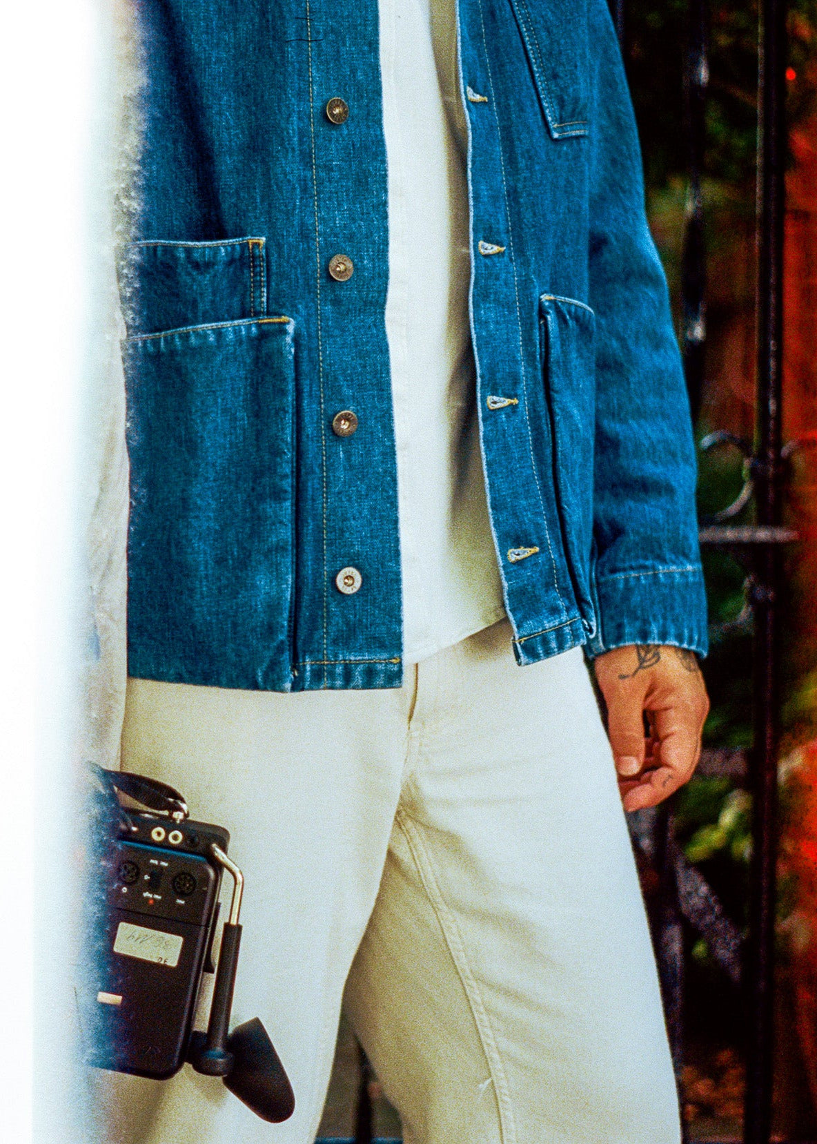 Person wearing a blue denim jacket and white pants with a blurred background
