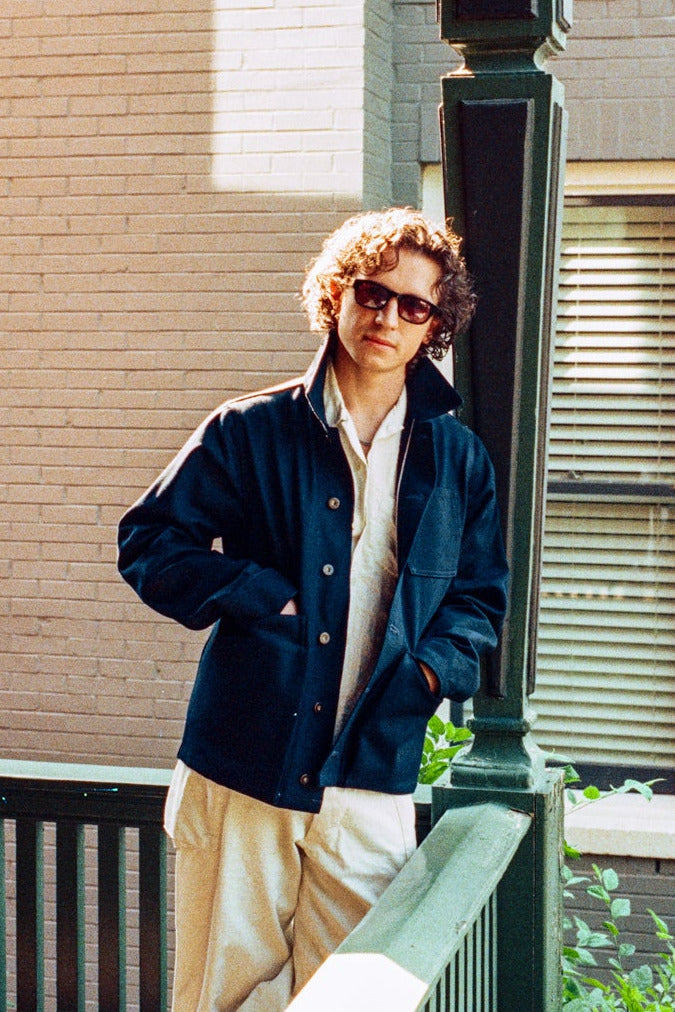 Person standing on a balcony with a building in the background